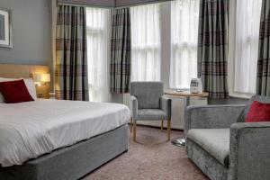 a hotel room with a bed, chair, desk and a lamp at Best Western Plus Oxford Linton Lodge in Oxford