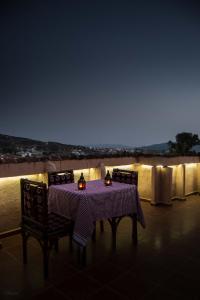 un tavolo e sedie su un balcone di notte di dar solaiman a Chefchaouen