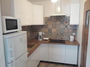 a kitchen with white cabinets and a microwave at Apartament Centrum in Mikołajki