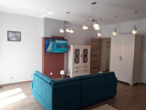 a living room with a blue couch and a tv at Apartament Centrum in Mikołajki