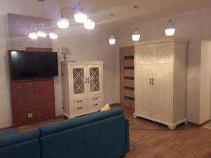 a living room with a blue couch and a tv at Apartament Centrum in Mikołajki