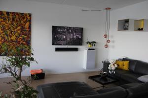 sala de estar con sofá negro y pared blanca en Ocean View Apartment en Aarhus
