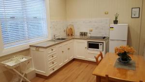 a kitchen with white cabinets and a table and a refrigerator at Arendon Cottage in Evandale