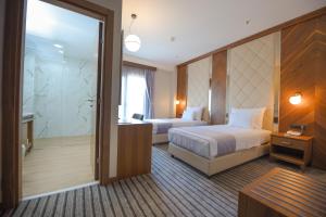 a hotel room with two beds and a walk in shower at Hotel Union in Podgorica