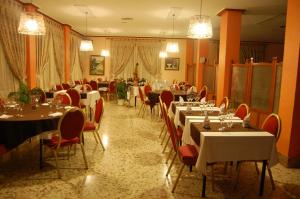 un restaurante con mesas blancas, sillas rojas y registrador en Hotel Balfagón, en Calanda