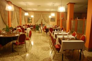 a restaurant with white tables and red chairs and tablesearcher at Hotel Balfagón in Calanda