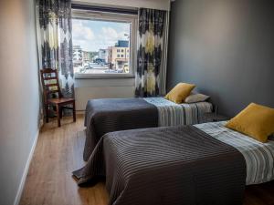 Dos camas en una habitación con ventana y silla. en Paasi & Kivi Apartments, en Rovaniemi