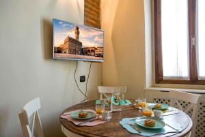 a dining room with a table and a tv on the wall at Ognissanti apartment in Florence