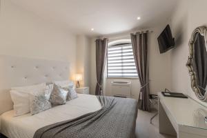 a bedroom with a bed with a desk and a window at Suites @ Portarade in Ferragudo