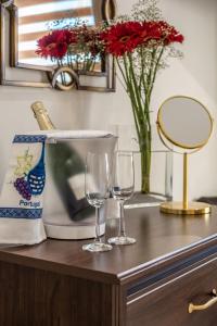 dos copas de vino en un mostrador con un jarrón con flores en Suites @ Portarade, en Ferragudo