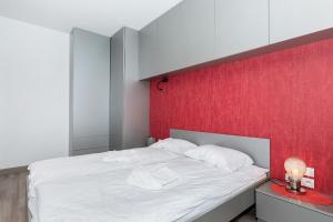 ポズナンにあるModern Apartment Poznań Dąbrowskiegoの赤い壁のベッドルーム1室(白いベッド1台付)