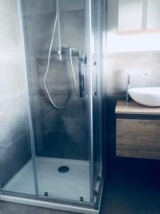 een douche met een glazen deur naast een wastafel bij appartamento piazza mazzini in Lido di Jesolo