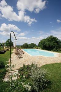 a swimming pool with chairs and a light pole at Agriturismo Le Calle in Cinigiano