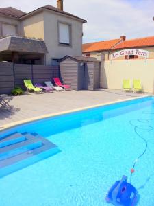 a swimming pool with chairs and a house at Logis Hotel Restaurant Le Grand Turc in LʼOie