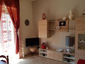 uma sala de estar com televisão e prateleiras de madeira em Stella Marina em Calatabiano