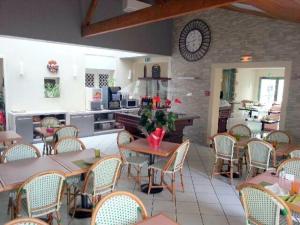 a restaurant with tables and chairs and a kitchen at Logis Hotel Restaurant Le Grand Turc in LʼOie