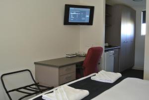 a room with a bed and a desk and a chair at Dooley's Tavern & Motel Springsure in Springsure