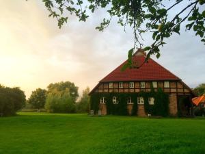 an old house with a red roof on a green field at Landhaus Schönhof in Feldberg