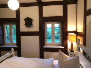 a bedroom with three windows and a bed and a clock at Landhaus Schönhof in Feldberg