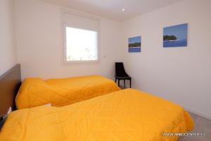 エンプリアブラバにあるLV02のベッドルームにオレンジカバー付きのベッド2台が備わります。