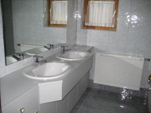 een witte badkamer met 2 wastafels en een spiegel bij Haus Kaiser in Passriach