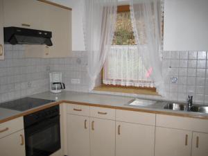een keuken met witte kasten, een wastafel en een raam bij Haus Kaiser in Passriach