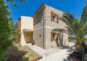 una vista exterior de una casa de piedra con una palmera en Picara, en Mancor del Valle