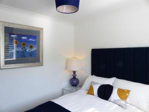 a bedroom with a white bed with a black headboard at Menhyr in Carbis Bay