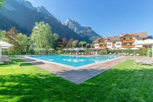 una piscina en un complejo con montañas en el fondo en Hotel La Maison Wellness & Spa en Alleghe