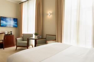 a hotel room with a bed and two chairs and a table at Hotel Savoy in Saint Helier Jersey