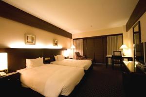 a hotel room with two beds and a television at Okinawa Kariyushi Beach Resort Ocean Spa in Onna