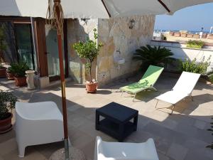 eine Terrasse mit Stühlen, einem Sonnenschirm und einem Tisch in der Unterkunft B&B Torrente Antico in Trani