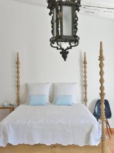 Un dormitorio con una cama con sábanas blancas y una lámpara de araña. en Mas du Perthus en Cassis
