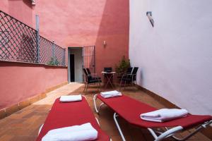Un balcón con 2 bancos rojos y una mesa. en Singular Pilatos, en Sevilla