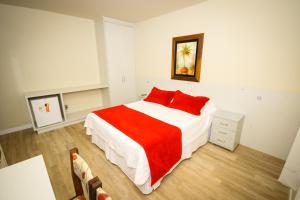 um quarto com uma cama grande e almofadas vermelhas em Hotel Geranium em Balneário Camboriú