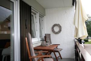 オーベルストドルフにあるAlpenflair Ferienwohnungen Whg 106の窓付きのポーチ(テーブル、椅子付)