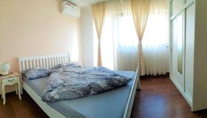 a bedroom with a bed with a blue comforter and a window at Holiday Home Ilidza in Sarajevo