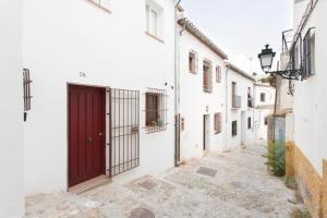 un callejón con una puerta roja en un edificio blanco en Montes Claros 26, en Granada