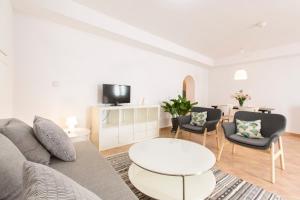 Una sala de estar con un sofá, una mesa y sillas. en Montes Claros 26, en Granada