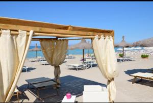 a canopy on a beach with chairs and umbrellas at Salento Sweet Home in Melissano