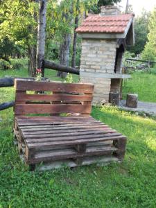 drewniana ławka siedząca w trawie obok ptasiego domku w obiekcie Holiday Home Jela w mieście Mrkopalj