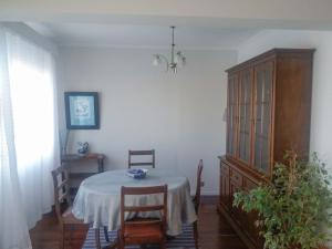 a dining room with a table and chairs and a cabinet at Varanda do Atlântico in Ponta Delgada