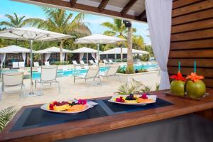 dos platos de fruta en una mesa junto a una piscina en Serenity at Coconut Bay - All Inclusive, en Vieux Fort