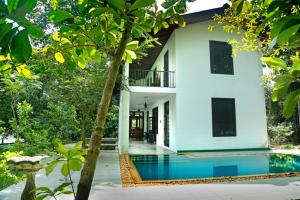 une maison avec une piscine en face de celle-ci dans l'établissement Villa by the Lake Bolgoda, Moratuwa-Colombo, à Moratuwa