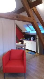 uma cadeira vermelha num quarto com uma cozinha em Le charme du château em Les Andelys