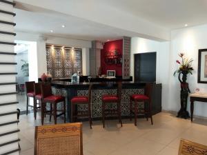 a kitchen with a bar with red walls and stools at Hotel María Jose in Mérida