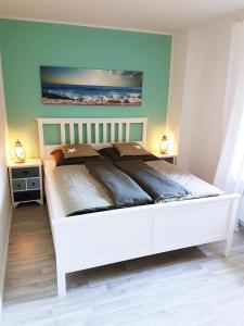 Una cama blanca en un dormitorio con dos lámparas. en Wellenreiter - das appartment, en Schönhagen