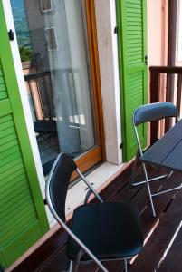 Duas cadeiras num alpendre com uma mesa e uma janela em Appartamento Campagnola 1 em Riva del Garda