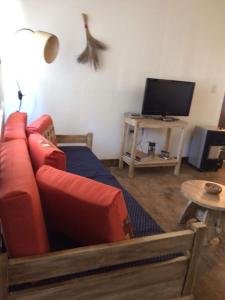 sala de estar con sofá rojo y TV en Allegra casas de campo en Vaqueros