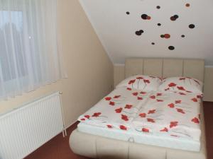 ein Schlafzimmer mit einem Bett mit einer weißen Bettdecke und roten Blumen in der Unterkunft Verona in Balatonmáriafürdő